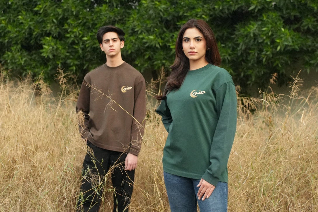 Two people standing in a field with greenery in the background